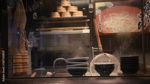 Japanese ramen kitchen Scene. Hot boiling Ramen pot with noodle strainers and steam of Ramen noodle restaurant with warm tone light that shows the Traditional Japanese.
