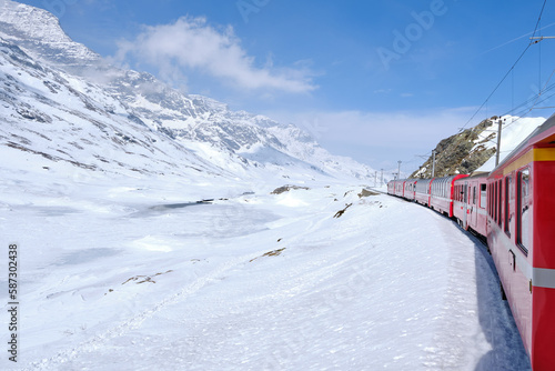 Bernina mountain pass. The famous red train is crossing the white lake. Amazing landscape of the Switzerland land. Famous destination and tourists attraction