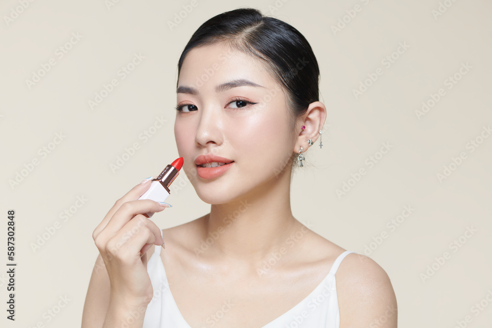 woman isolated on beige background holding red lipstick woman isolated on beige background holding red lipstick