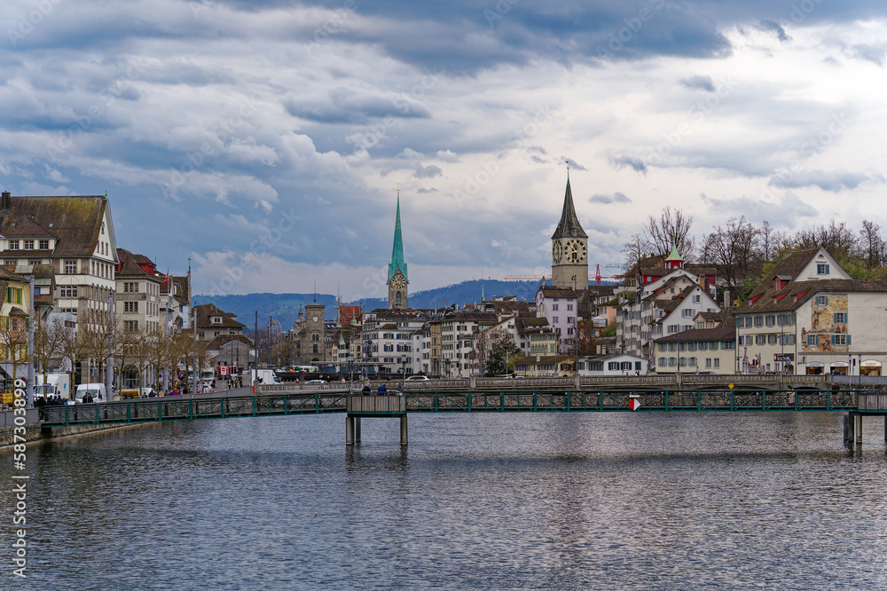 Scenic view of the old town of City of Zürich with Limmat River, quayside and footbridge on a cloudy spring day. Photo taken March 31st, 2023, Zurich, Switzerland.