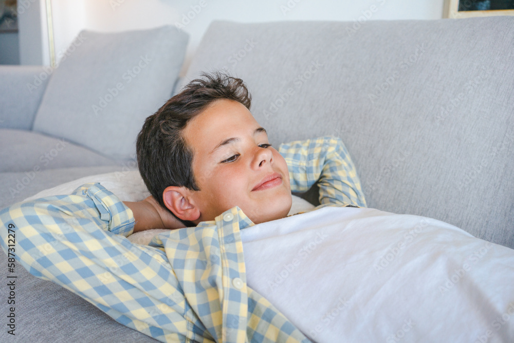Relaxed boy resting lying on a couch with the hands on the head at home Relaxed boy resting lying on a couch with the hands on the head at home