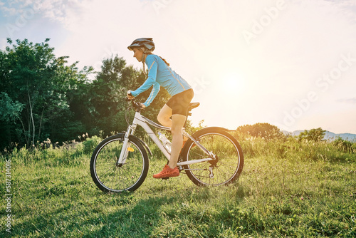 Cyclist Woman riding bike go in sports outdoors on sunny day a mountain in the forest. Silhouette female at sunset. Fresh air. Health care, authenticity, sense of balance and calmness. 