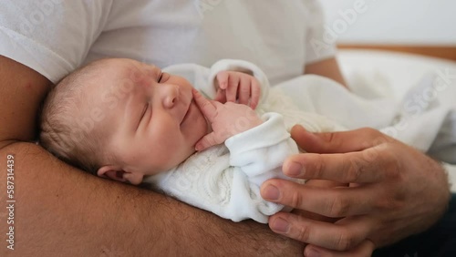 Adorable newborn baby yawning lying on his father legs and falling asleep. Closeup view of sweet infant child and parent dad. Moments of fatherhood