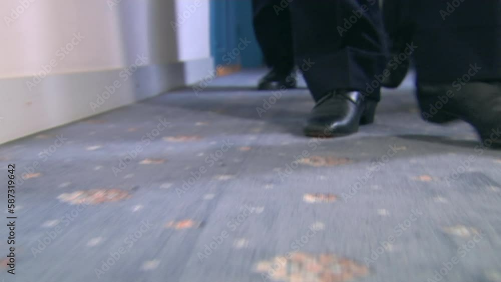 View of three pairs of men's feet walking on old carpet View of three pairs of men's feet walking on old carpet
