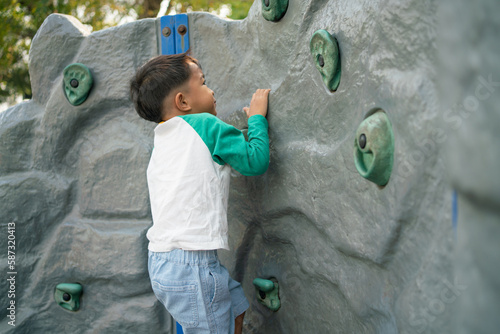 Happy asian boy climbing in outdoor playground public park