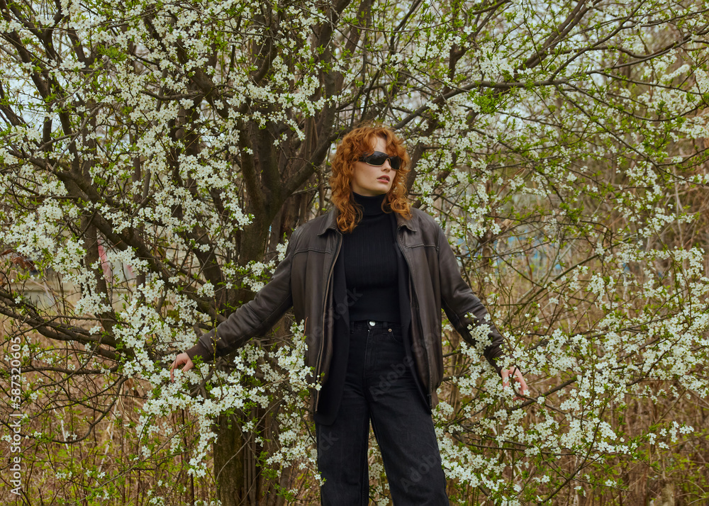 a stylish woman in a black suit and sunglasses walks in the park in the warm season a stylish woman in a black suit and sunglasses walks in the park in the warm season