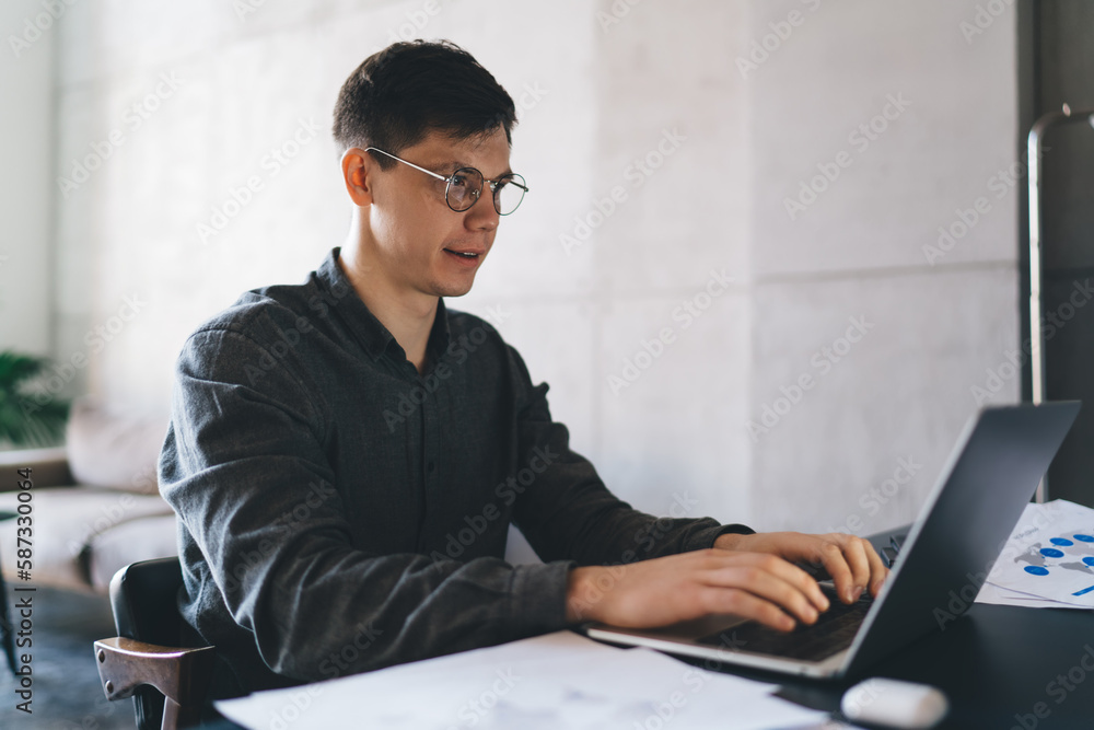 Positive man typing on laptop in office Positive man typing on laptop in office