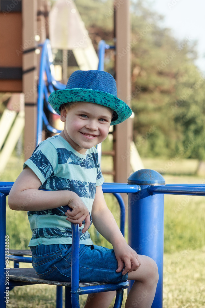 Portrait of a smiling boy in blue clothes on a blue carousel. Vertical photo. Portrait of a smiling boy in blue clothes on a blue carousel. Vertical photo.