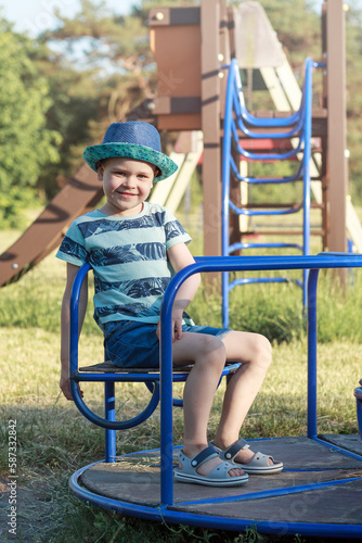 Portrait of a smiling boy in blue clothes on a blue carousel. © Linas T