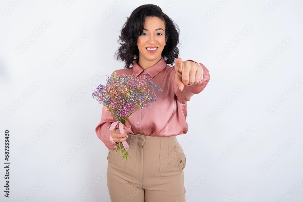 young woman holds big bouquet of nice flowers over white background pointing at camera with a satisfied, confident, friendly smile, choosing you young woman holds big bouquet of nice flowers over white background pointing at camera with a satisfied, confident, friendly smile, choosing you