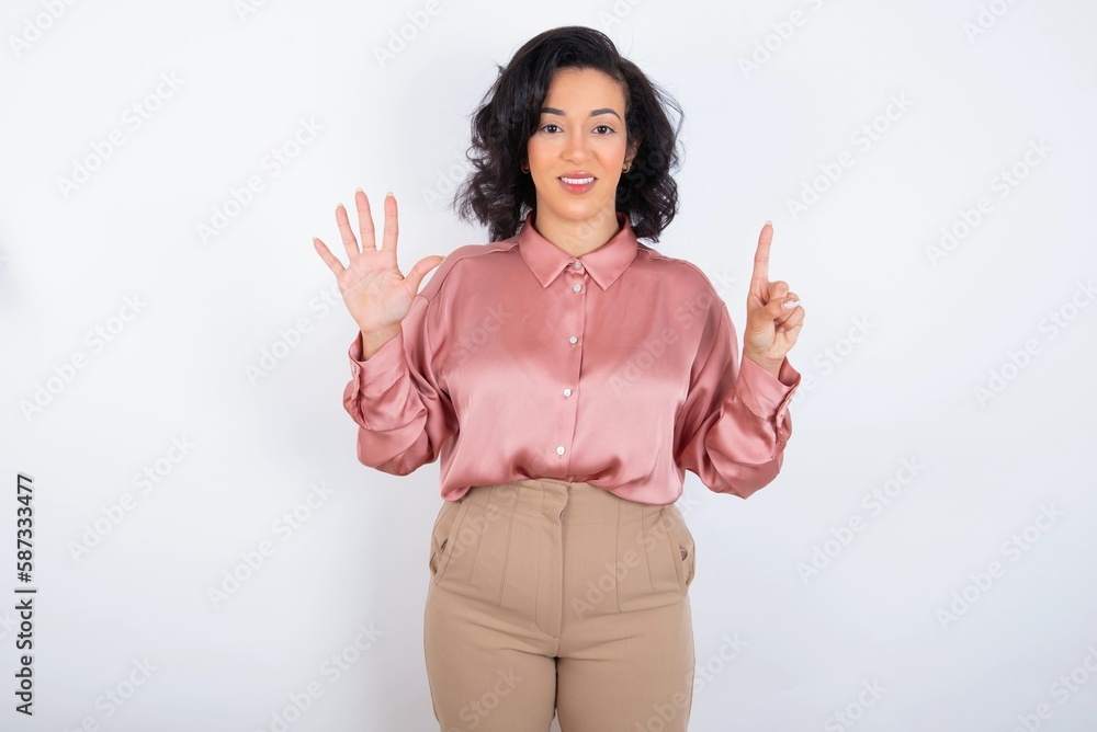 young woman holds big bouquet of nice flowers over white background showing and pointing up with fingers number six while smiling confident and happy. young woman holds big bouquet of nice flowers over white background showing and pointing up with fingers number six while smiling confident and happy.