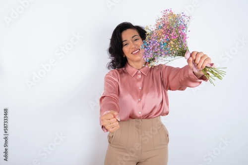 young woman holds big bouquet of nice flowers over white background imagine steering wheel helm rudder passing driving exam good mood fast speed