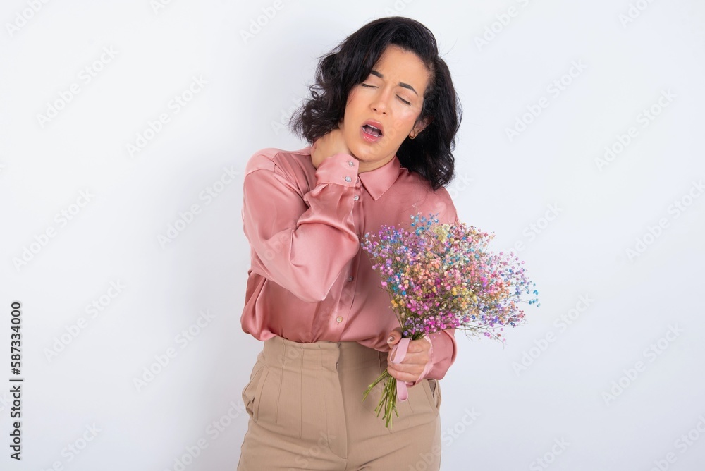 young woman holds big bouquet of nice flowers over white background Suffering of neck ache injury, touching neck with hand, muscular pain young woman holds big bouquet of nice flowers over white background Suffering of neck ache injury, touching neck with hand, muscular pain