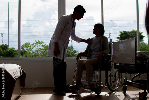 caucasian man doctor is examining the female older patient in wheelchair the hospital.