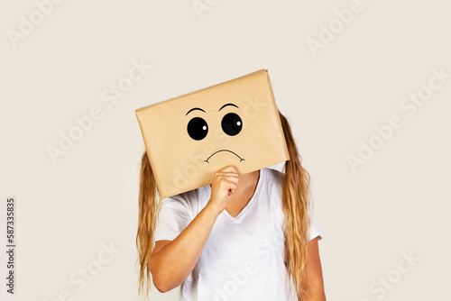 Mujer con caja de cartón en la cabeza con gesto pensativo preocupante sobre fondo gris liso brillante y aislado. Vista de frente y de cerca. Copy space