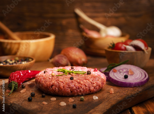 Stek z mięsa mielonego do hamburgera z przyprawami, cebula, papryka na starych deskach