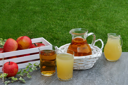 Ein Glas und Krug gefüllt mit Apfelsaft auf einem Tisch im Garten.