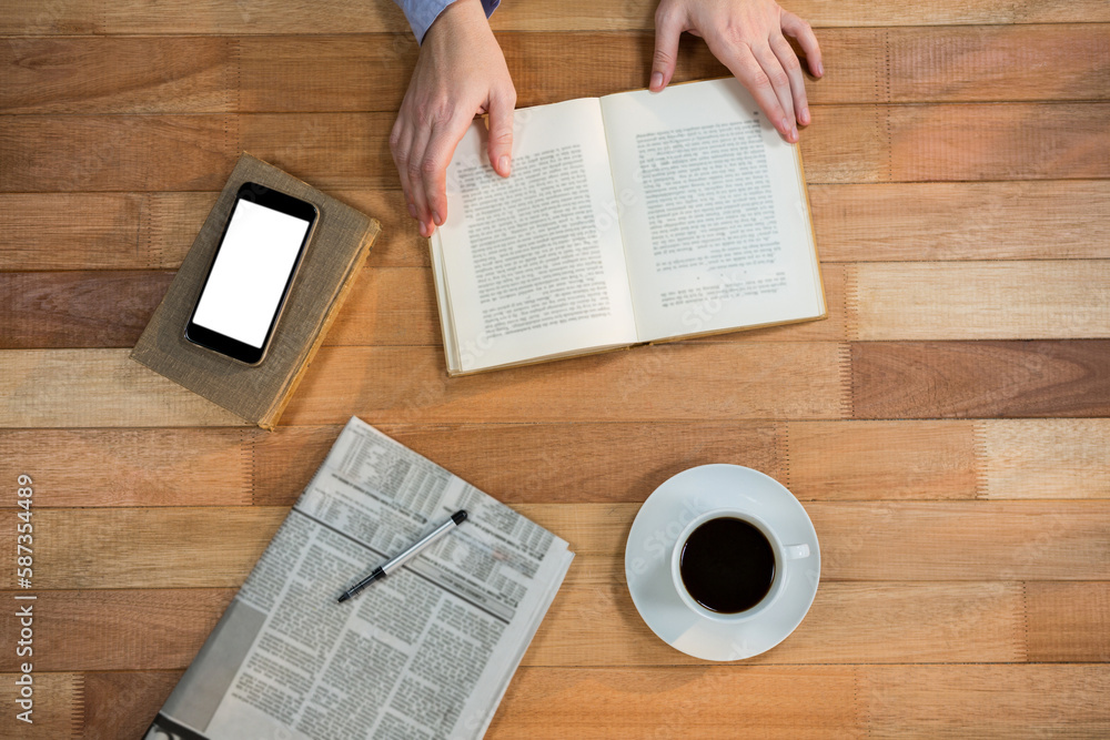 Obraz premium Cropped image of hand holding book at her desk