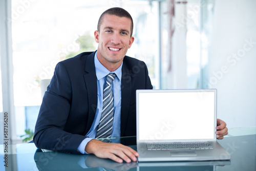 Portrait of smiling businessman showing laptop