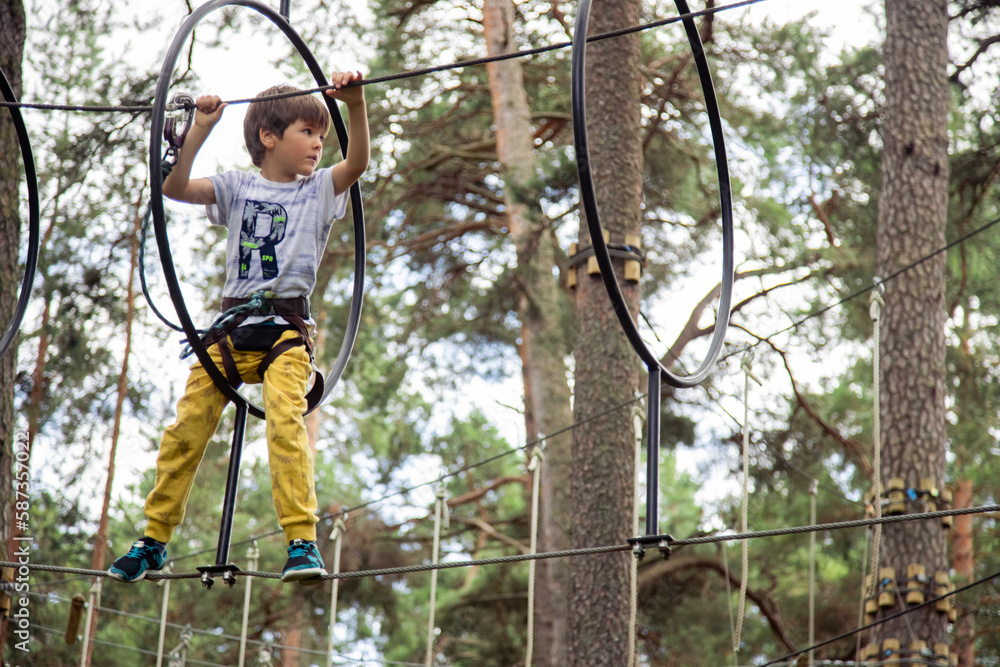 Obraz premium Child in yellow pants climbing in a rope park