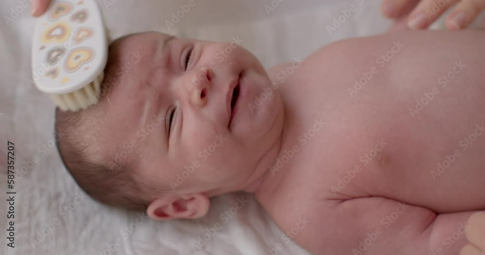 A portrait of a small child being scratched on the head with a brush. Combing the hair of a newborn baby. Hygiene and human care. Children's look. A portrait of a small child being scratched on the head with a brush. Combing the hair of a newborn baby. Hygiene and human care. Children's look.