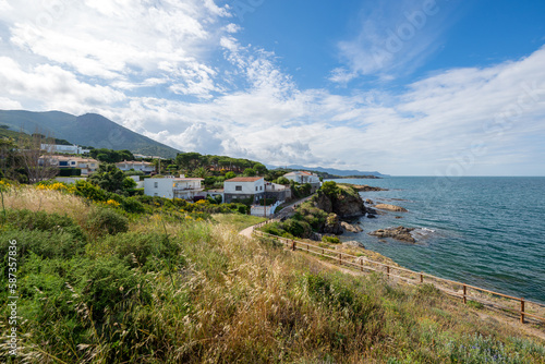 View of the coastal village of El Port de la Vall and the Pyrenees mountains in the background on a sunny day with a cloudy sky - June 2018 - Costa Brava, Catalonia, Spain