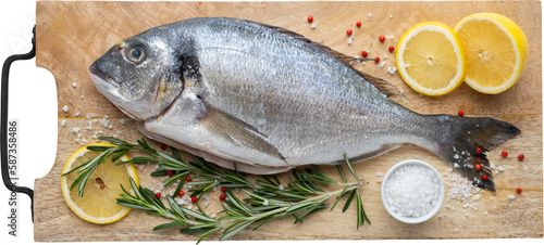 Photography Dorado fish with lemon slices, salt and rosemary on cutting board
