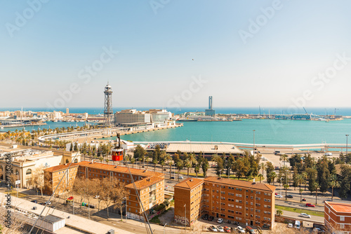 View of Barcelona from the hill. Sea and horizon. People ride in a red cabin on a cable car into the distance. Tourism in Spain. Transport type. At a bird's eye view.