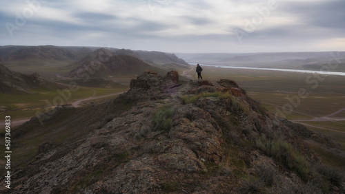 man on a rock overlooking the rivers and the valley in windy gloomy weather. landscape of Kazakhstan in the Canyon of the Ili River