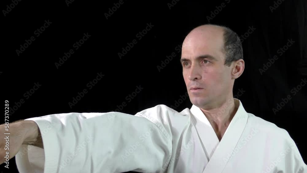 On a black background, an adult athlete performs punches On a black background, an adult athlete performs punches
