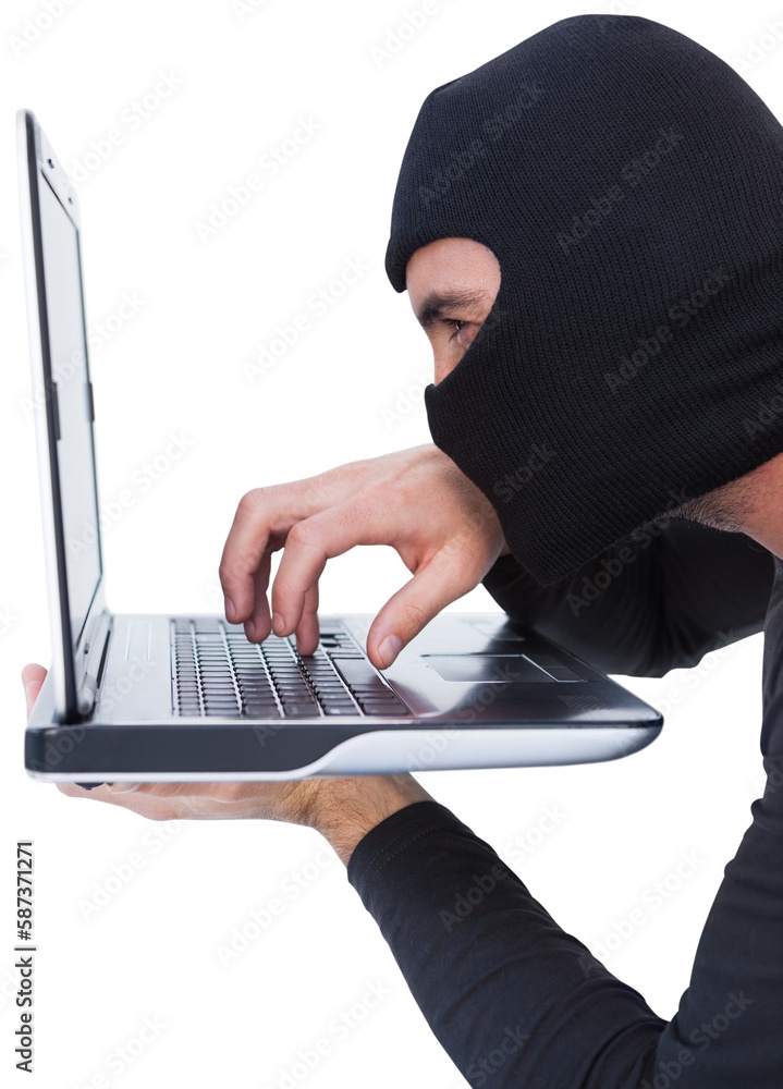 Focused burglar with balaclava typing on laptop Focused burglar with balaclava typing on laptop