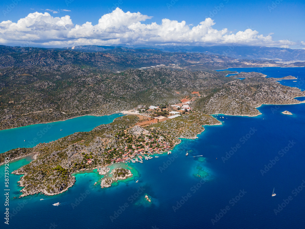 Aerial drone shot of Simena Castle (Kaleköy), beach, and yachts, displaying the historic site and enchanting Mediterranean landscape in Antalya, Turkey.