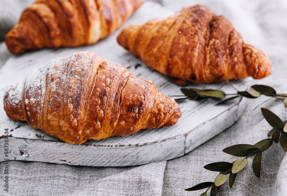 Close up three freshly baked croissants with sugar powder on a wooden desk Close up three freshly baked croissants with sugar powder on a wooden desk