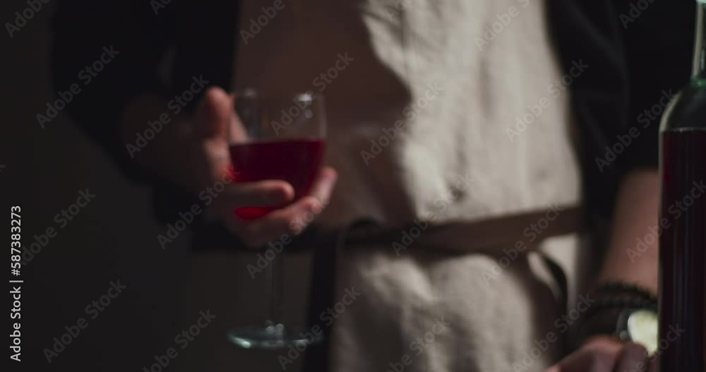 Bartender in apron grabbing and re-serving a nice glass of red win at a bar, close up Bartender in apron grabbing and re-serving a nice glass of red win at a bar, close up