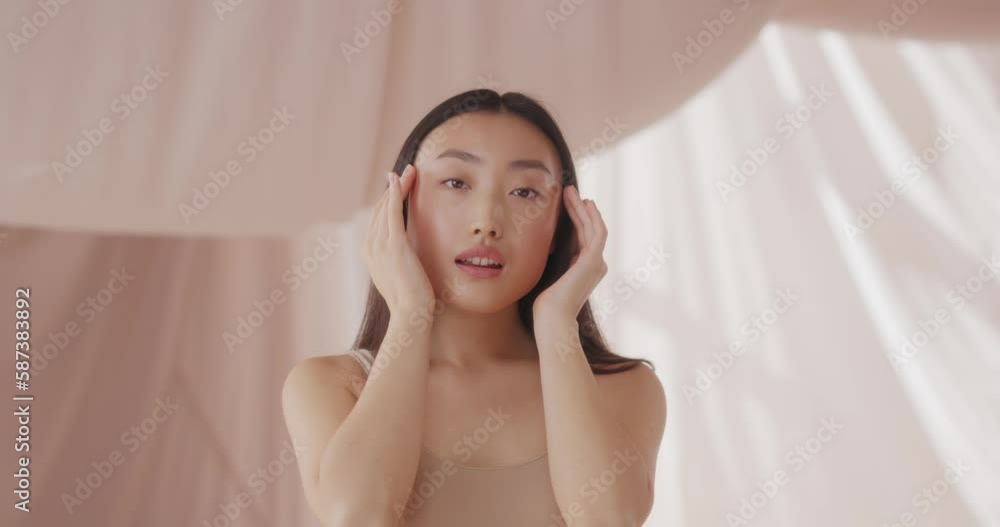 Attractive Asian woman posing to camera. Pretty girl having healthy, soft skin after cosmetic product. Hand touching beauty, smooth and elastic face. Perfect skin. Dermatology concept. Attractive Asian woman posing to camera. Pretty girl having healthy, soft skin after cosmetic product. Hand touching beauty, smooth and elastic face. Perfect skin. Dermatology concept.