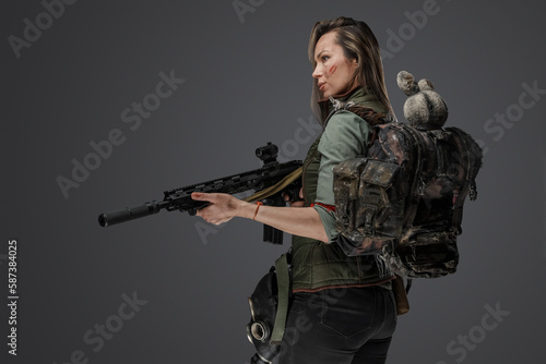 Fotografie Studio shot of attacking female mercenary with backpack and rifle