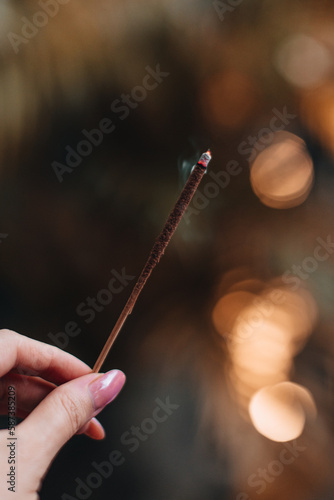 Female hand holding burning incense. Aromatherapy smoke