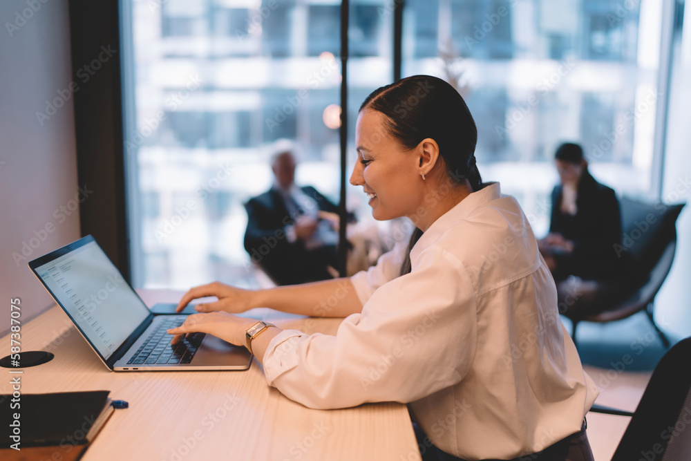 Smiling woman working on laptop in office at desk Smiling woman working on laptop in office at desk