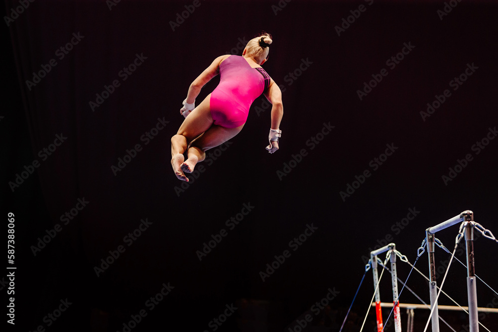 female gymnast performing somersault gymnastics on uneven bars, black background, sports summer games