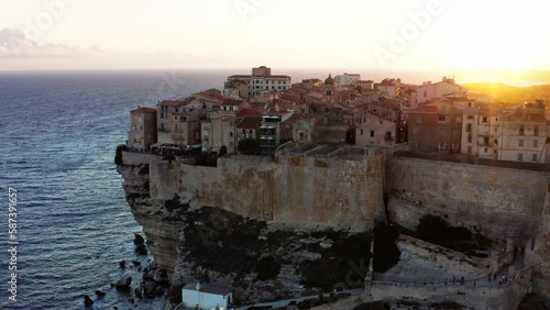 Bonifacio, Corsica. The aerial view during sunset displays a breathtaking palette of warm hues, with the ancient citadel perched on a cliff overlooking the turquoise waters of the Mediterranean.