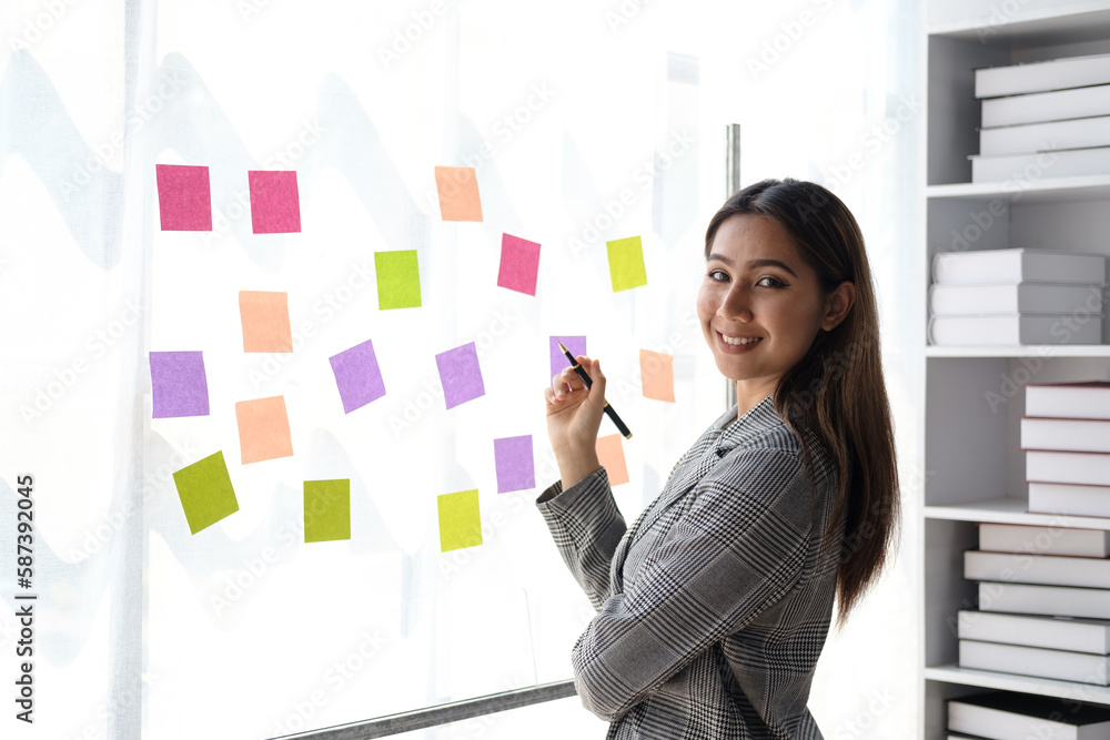 Successful smiling businesswoman writing note on post-it at office. Successful smiling businesswoman writing note on post-it at office.