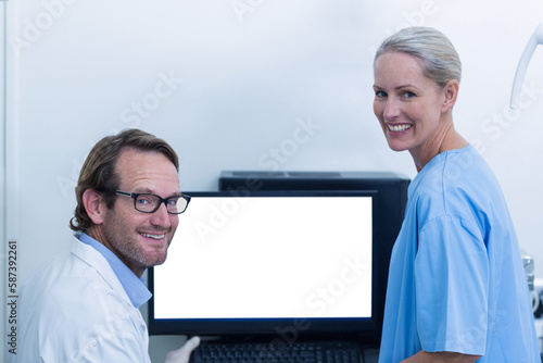 Portrait of dentist and dental assistant discussing xray on the monitor