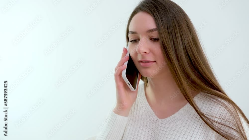 Smiling thousand-year-old woman talking on the phone at home, happy young girl holding a cell phone answering a call, an attractive teenager pleasantly talking on a cell phone with friend Smiling thousand-year-old woman talking on the phone at home, happy young girl holding a cell phone answering a call, an attractive teenager pleasantly talking on a cell phone with friend