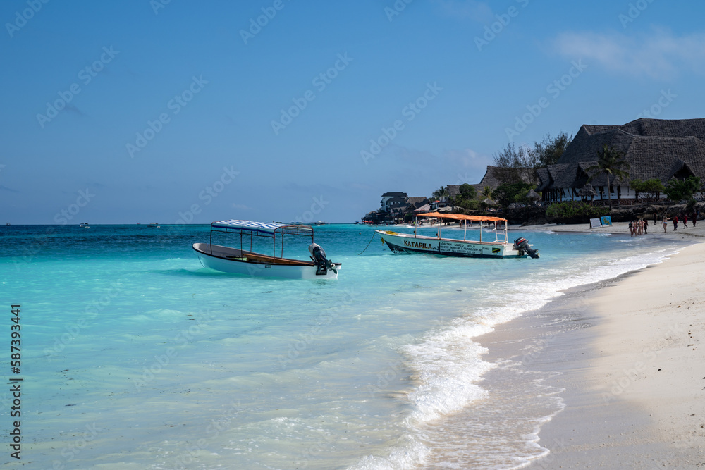 Fototapeta premium Zanzibar, Tanzania - Boats near the shoreline of the Indian Ocean, near a luxury resort