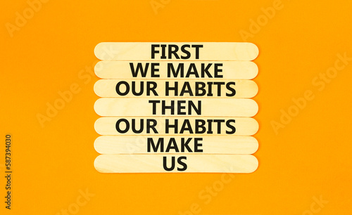 Our habits symbol. Concept words First we make our habits then our habits make us on wooden stick. Beautiful orange table orange background. Copy space. Motivational business our habits concept. photo
