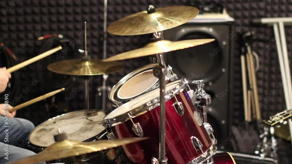 A musician drummer plays a drum kit in a recording studio. Drumming in the rehearsal base A musician drummer plays a drum kit in a recording studio. Drumming in the rehearsal base
