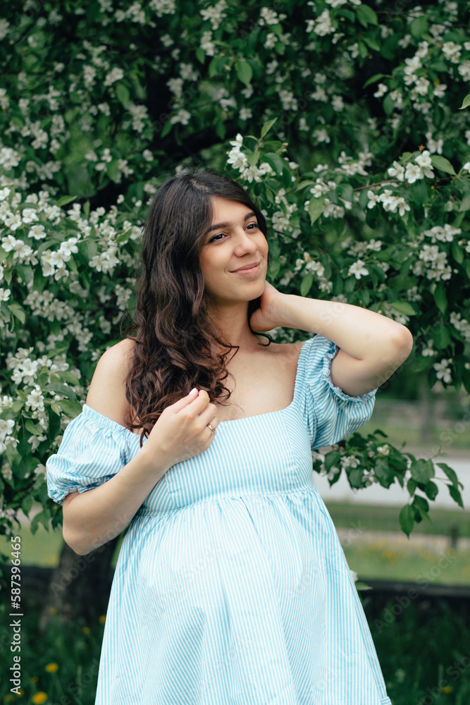 Portrait of a beautiful young pregnant woman in blooming apple trees.Spring,beauty,women's health concept. Portrait of a beautiful young pregnant woman in blooming apple trees.Spring,beauty,women's health concept.
