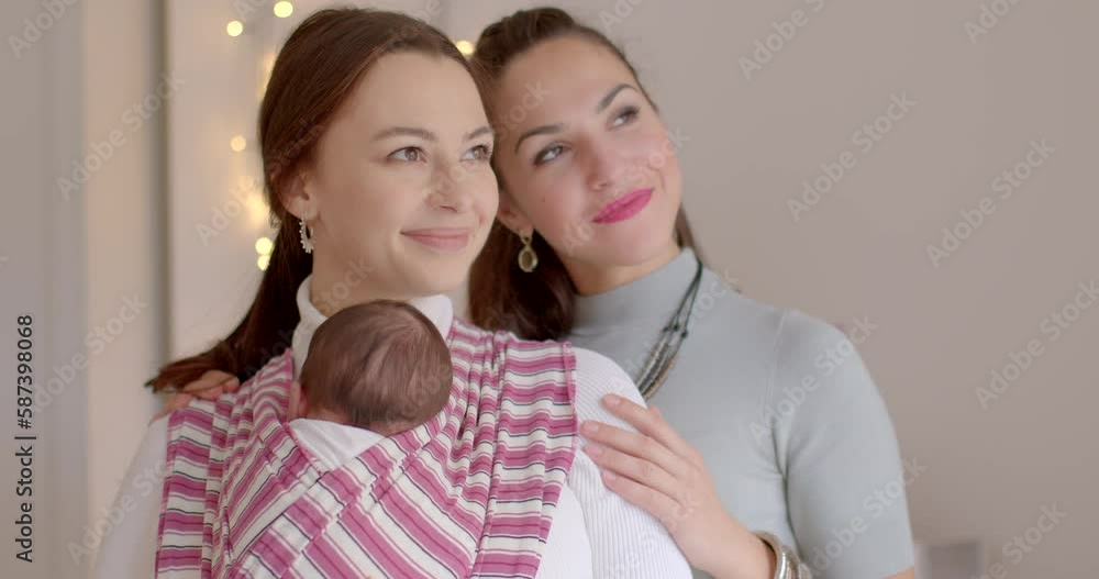 Two family partners of a woman look out the window. She is holding the baby in a carrier. Shared dreams and desires. Mental adjustment for acceptance of the child. Hug with hands. Two family partners of a woman look out the window. She is holding the baby in a carrier. Shared dreams and desires. Mental adjustment for acceptance of the child. Hug with hands.