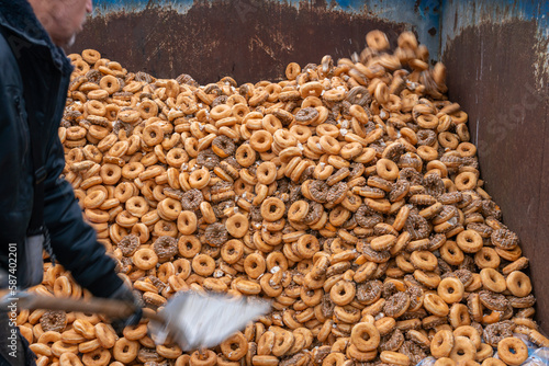 Many sweet and tasty round doughnuts, ring donuts covered with sugar. Chocolate-frosted doughnut. Symbol of sweeties, fried dough. A lot of sweet unhealthy food. Food waste, food production.