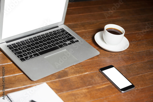 Laptop with mobile phone and coffee cup on wooden desk